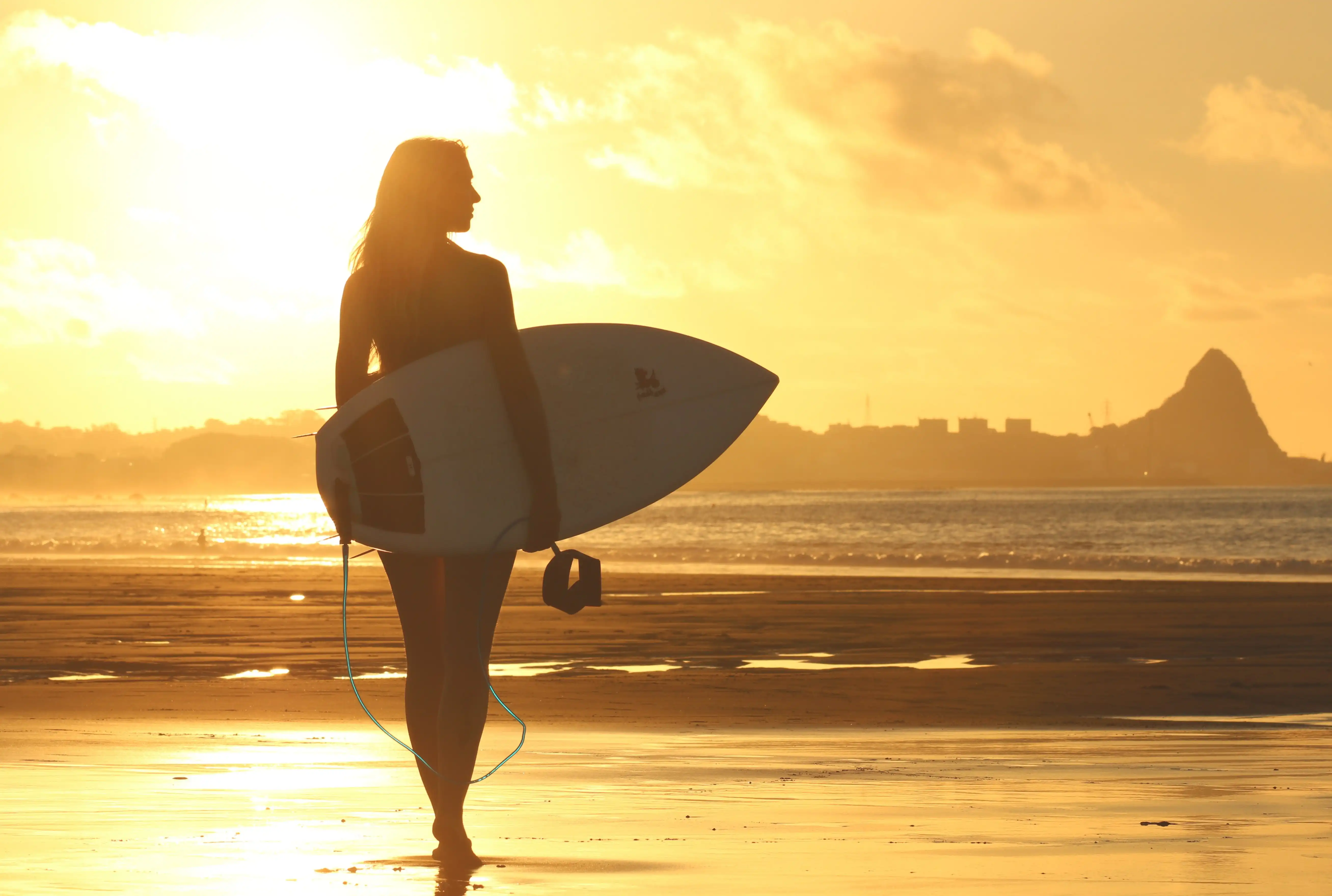 Person with surfboard at sunset